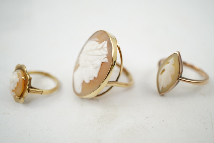 A group of three shell cameo rings, two depicting a classical lady in profile, one of navette-shaped outline depicting a dancing figure, each mounted in gold, two stamped 9ct, largest size V, largest cameo 3 x 2.4cm, com